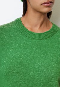 Vihreä neulepusero, jossa on ribbed pyöreä kaula-aukko, valmistettu pehmeästä kankaasta, jossa on hieman teksturoitu pinta. Ei näkyviä kuvioita tai yksityiskohtia.