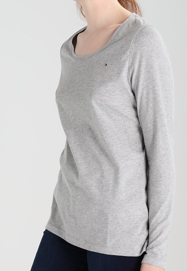 Grauer Langarm-T-Shirt mit Rundhalsausschnitt, aus weichem Material gefertigt, mit einem kleinen Logo-Akzent auf der Brust und einer lockeren Passform.