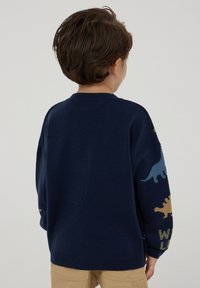 Maglione lavorato a maglia blu navy con motivi colorati di dinosauri sulle maniche, collo rotondo e vestibilità ampia; realizzato in tessuto morbido per comfort.