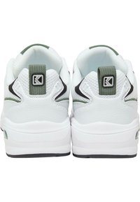 Fehér sneakers zöld és fekete kiegészítőkkel, texturált anyagokkal, párnázott bokapánttal és logós díszítéssel a sarkán. Lekerekített orr és párnázott talp.