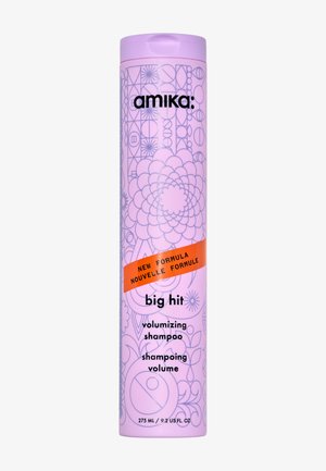 Bouteille de shampooing cylindrique violette avec des motifs floraux et géométriques, étiquette orange indiquant "Nouvelle Formule" et texte noir pour la marque et le nom du produit.