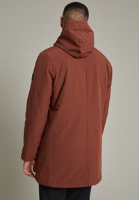 Parka izolată maro cu guler înalt și glugă. Prezintă o textură netedă, buzunare laterale și un design minimalist fără embellishments.