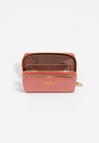 Cartera de piel rosa con cierre de cremallera, que presenta un logotipo dorado y un interior marrón con múltiples compartimentos y ranuras para tarjetas.