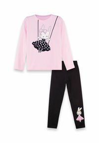 Top a maniche lunghe rosa con grafica di coniglio nero su un vestito a pois. Leggings neri con un piccolo coniglio bianco sulla caviglia.