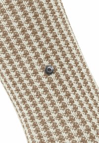 Bruin en witte houndstooth-geprint stof met een kleine ronde metalen knop met het label "Burlington The Original" gecentreerd op de stof.