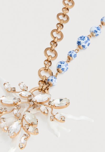 Χρυσό κολιέ αλυσίδα με μπλε και λευκές χάντρες σε σχέδιο λουλουδιών και μενταγιόν σε σχήμα λουλουδιού επενδυμένο με κρύσταλλα και μικρές λευκές λεπτομέρειες που μοιάζουν με κοράλλι.
