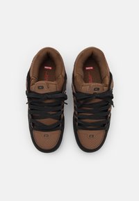 Baskets marron avec une surface texturée, des lacets noirs et des détails perforés. Comprend un logo discret et une doublure intérieure rembourrée.