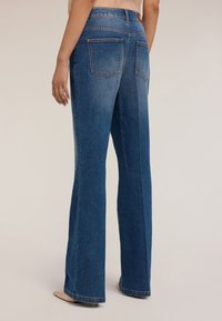 Jeans dżinsowe w kolorze niebieskim, z wysokim stanem, rozszerzane ku dołowi, z delikatnym odcieniem, posiadające dwie tylne kieszenie i postrzępiony brzeg. Materiał o wyraźnej strukturze i gładkiej fakturze.