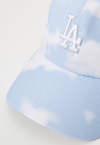 Blå tie-dye basecap med hvid broderet "LA" logo, lavet af bomuldsstof, struktureret form, buet skygge og synlige syninger.