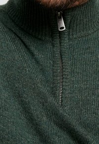 Ciemnozielony, dziergany sweter z wysokim kołnierzem i półzamkiem. Faktura prążkowana, z subtelnym wzorem i metalicznym zamkiem.