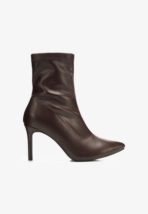 Dunkelbraune Leder-Stiefelette mit spitz zulaufender Zehenpartie und schlankem hohen Absatz, glattes Obermaterial mit dezentensteppnähten.