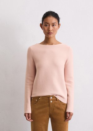 Lichtroze lange mouw trui met een bootnek en een gestructureerde stof, gecombineerd met bruine corduroy broek met knopensluiting.