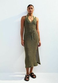 Abito lavorato a maglia verde oliva con scollo a V, spalline regolabili, cintura in vita e spacco laterale, realizzato in un tessuto strutturato.