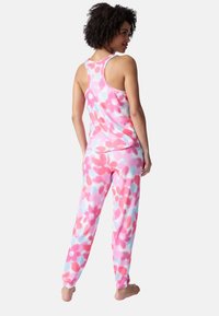 Ensemble de vêtements de nuit à motif floral comprenant un haut sans manches et un pantalon long, confectionné dans un tissu doux aux teintes rose, rouge et bleu.