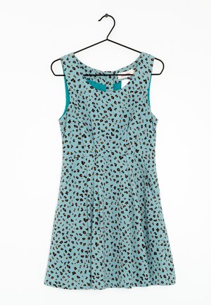 En ærmeløs kjole med en teal-basis og sort og orange leopardmønster. Den har en tætsiddende liv og en udslået nederdel, hængende på en sort bøjle.