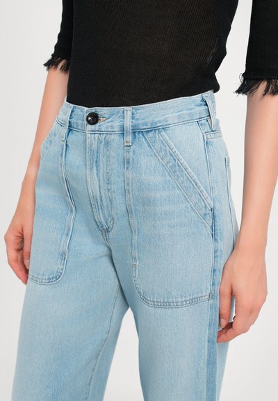 Light blue denim high-waisted jeans with angled front pockets, a single black button at the waist, and subtle faded texture.