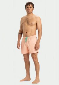 Vīriešu peldbikses gaiši rozā audumā ar struktūru. Tām ir elastīga josta un tirkīza krāsas aukliņa regulēšanai.