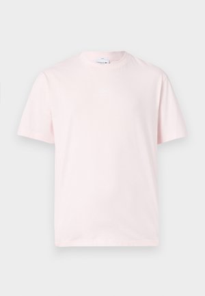 Jasnoróżowy t-shirt z krótkim rękawem i okrągłym dekoltem z małym wytłaczanym logo na piersi, prezentowany na jednolitym tle.