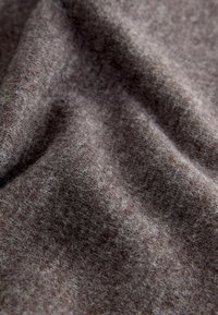 Textúrovaná tkanina v tlmenom hnedom odtieni, ktorá má mäkký pocit a jemné farebné odtiene, čo zdôrazňuje jej tkanú kvalitu a hĺbku.