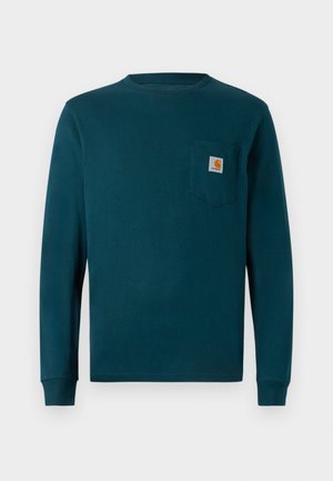 Langærmet skjorte i mørk teal bomuld, med rund hals og en brystlomme til venstre med en firkantet logo-patch. Simpelt, ensfarvet design.