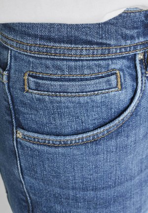 Nahaufnahme von blauen Jeans mit sichtbarer Naht und Nieten an der Gesäßtasche.
