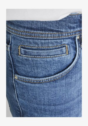 Nahaufnahme von blauen Jeans mit sichtbarer Naht und Nieten an der Gesäßtasche.