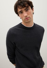 Maglione grigio scuro lavorato a maglia con scollo rotondo e maniche lunghe. Tessuto con texture e dettagli a costine ai polsi e all'orlo.