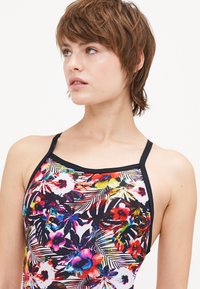 Maillot de bain floral coloré avec un fond noir, présentant des imprimés tropicaux éclatants. Conçu avec des bretelles fines et une silhouette ajustée.