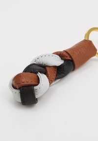 Flettet nøglering lavet af læder i sorte, brune og grå nuancer. Har en guldfarvet metalring og en struktureret overflade på læderet.