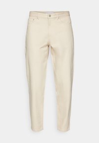 Pantalones de algodón beige con un ajuste tapered, con cierre de botón y dos bolsillos laterales. Textura suave con detalles de costura mínimos.