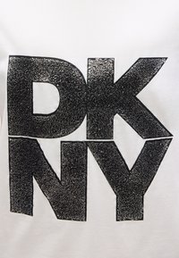 Λευκό μπλουζάκι με μεγάλα μαύρα υφή γράμματα "DKNY" που διαθέτουν μεταλλικό στοιχείο και ομαλή φινίρισμα γύρω από τις άκρες.