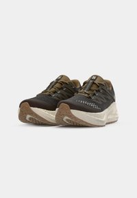 Athletic shoes made of mesh and synthetic materials, featuring a black and brown color scheme, textured sole, and contrasting white accents.
