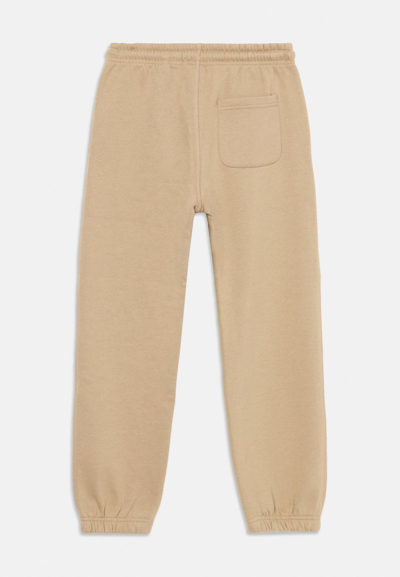 Beige Jogginghose mit elastischem Bund, elastischen Bündchen und einer einzelnen Gesäßtasche. Hergestellt aus weichem, gestricktem Stoff mit einer glatten Textur.