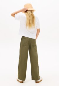 Λευκό μπλουζάκι με κοντά μανίκια, χακί φαρδιά παντελόνια και ένα ανοιχτό πορτοκαλί καπέλο τύπου bucket. Καθημερινό, χαλαρή εφαρμογή με λεία υφή.