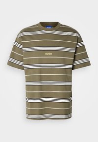 T-shirt olive vert à manches courtes avec des rayures horizontales noires et blanches, présentant un col rond et un petit logo doré "Hugo" sur la poitrine.