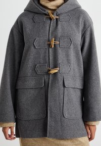 Grå duffelcoat lavet af uld med hætte, der har træknap-lukninger, to forlommer og ribbede ærmegab. Enkel, struktureret stof.