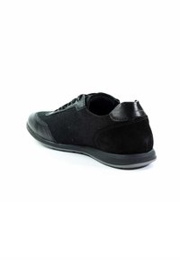 Schwarze Sportlichkeit mit einem Obermaterial aus Mesh, Suede-Akzenten, einer glatten Lederferse und einer Gummisohle mit runder Form. Schnürsenkel sichtbar.