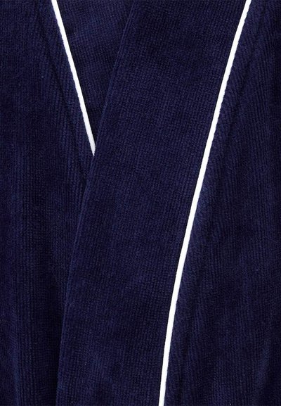 Κοντινή λήψη υφάσματος από σκουρό μπλε πετσέτα με λευκό περίγραμμα κατά μήκος των άκρων, που δείχνει υφή και πτυχώσεις.