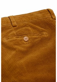 Corduroy broek in warme mosterdkleur met verticale ribbels, voorzien van een achterzak die wordt gesloten door een ronde, lichtgekleurde knoop.