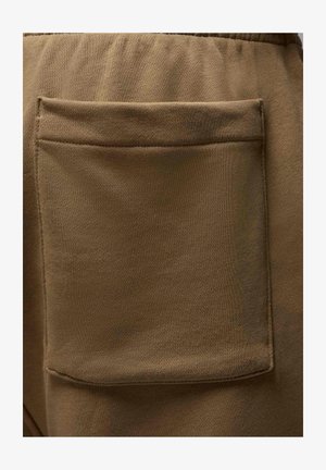 Brauner Stoff mit einer glatten Textur hat eine große, rechteckige Tasche, die auf die Rückseite genäht ist und von einer subtilen Naht umrandet wird.