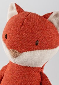 Stuffed fox toy with a textured orange knit body, cream-colored muzzle, and ears. Small brown stitched eyes and nose.