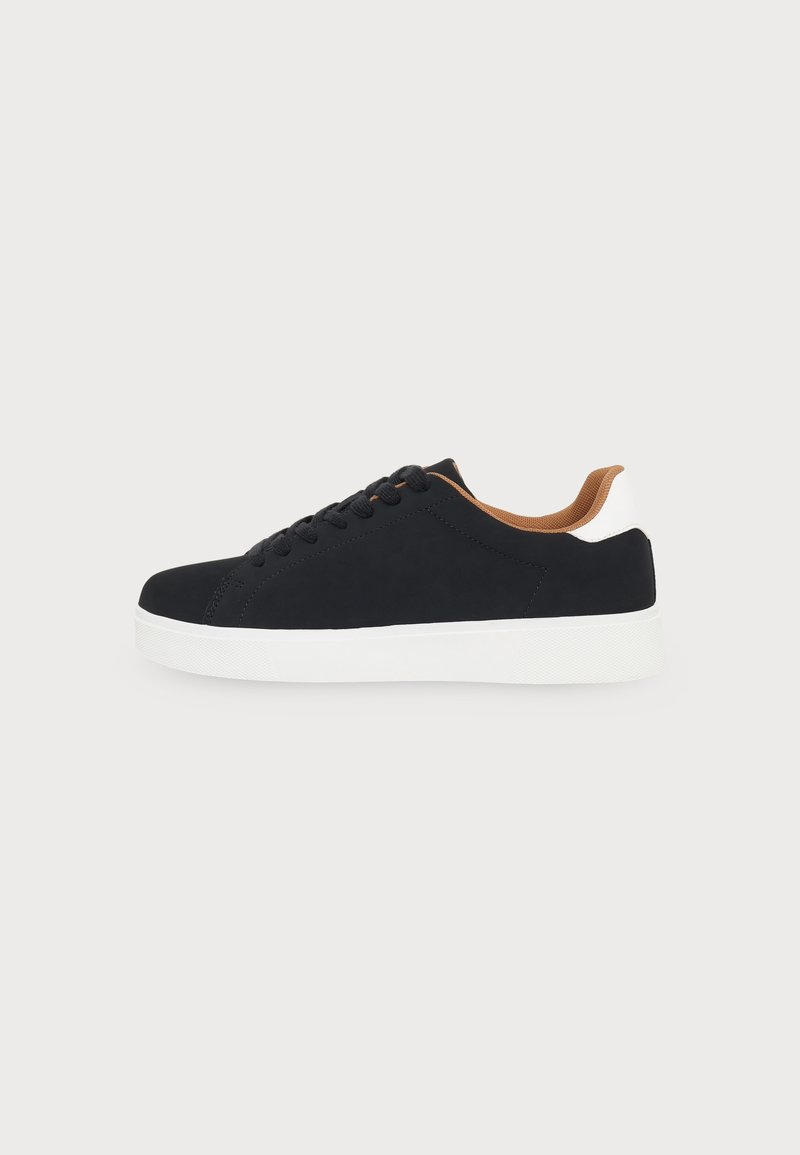 Baskets basses noires avec semelle blanche, lacets noirs, doublure intérieure marron et languette au talon, vues de côté.