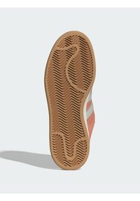 Suola di sneaker in gomma con un motivo a spina di pesce, caratterizzata da una superficie testurizzata di colore marrone chiaro e un accento rosa sulla parte superiore.