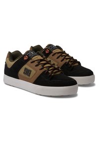 Melnas un brūnas snekeres ar zamšādas un tekstila augšdaļu, kontrastējošām šņorēm, gumijas zoli un zīmola logotipu sānos.