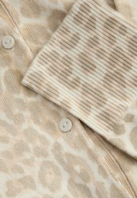 Cardigan tricoté à imprimé léopard beige doux et crème avec poignets de manches côtelés et boutons crème.