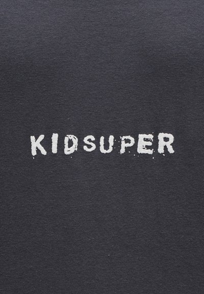 Μαύρο βαμβακερό t-shirt με το κείμενο "KIDSUPER" σε λευκή φθαρμένη εκτύπωση, τοποθετημένο κεντρικά στο μπροστινό μέρος. Μαλακή υφή.