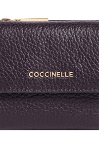Portafoglio in pelle marrone scuro con texture a ciottoli, logo in metallo dorato "COCCINELLE" e dettagli in dorato alla zip sulla parte superiore.