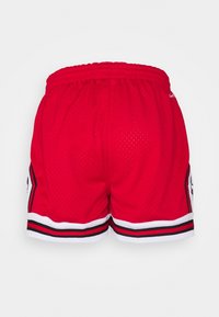 Pantalones cortos de baloncesto rojos hechos de tela de malla. Presentan un ribete blanco y negro a lo largo del dobladillo y los lados. Cintura elástica para mayor comodidad.