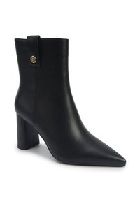 Bottines en cuir noir avec un bout pointu, un talon bloc et une sangle décorative avec un bouton doré près du haut, sur un fond blanc.