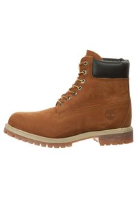Botte en cuir marron avec un col rembourré noir, œillets en métal et une semelle en caoutchouc robuste. Présente un logo et un panneau texturé sur le côté.